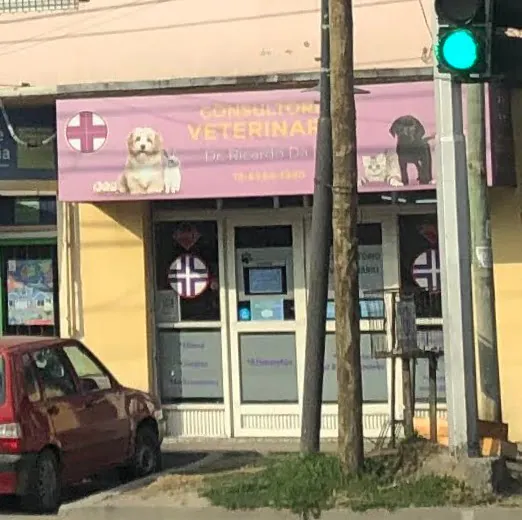 Frente del consultorio, con el cartel rosa de «Consultorio veterinario» y la cruz en la vidriera